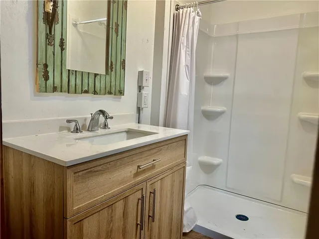 a bathroom with a sink a toilet a mirror and shower