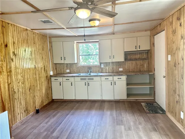 a kitchen with cabinets wooden floor and a window
