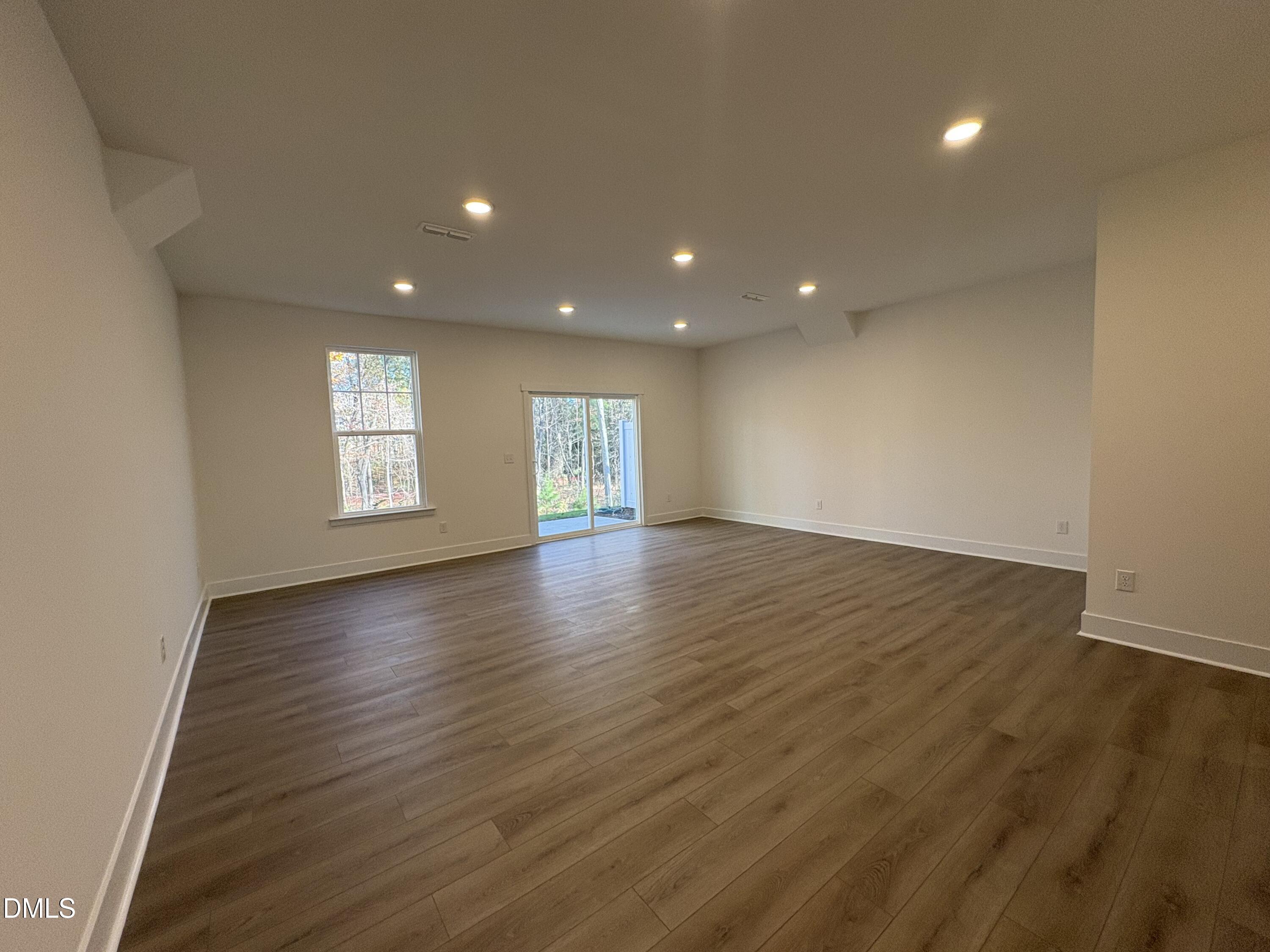 6046 Dunzo Drive Raleigh, NC 27617 - Photo 22 of 44 an empty room with wooden floor and windows with curtains