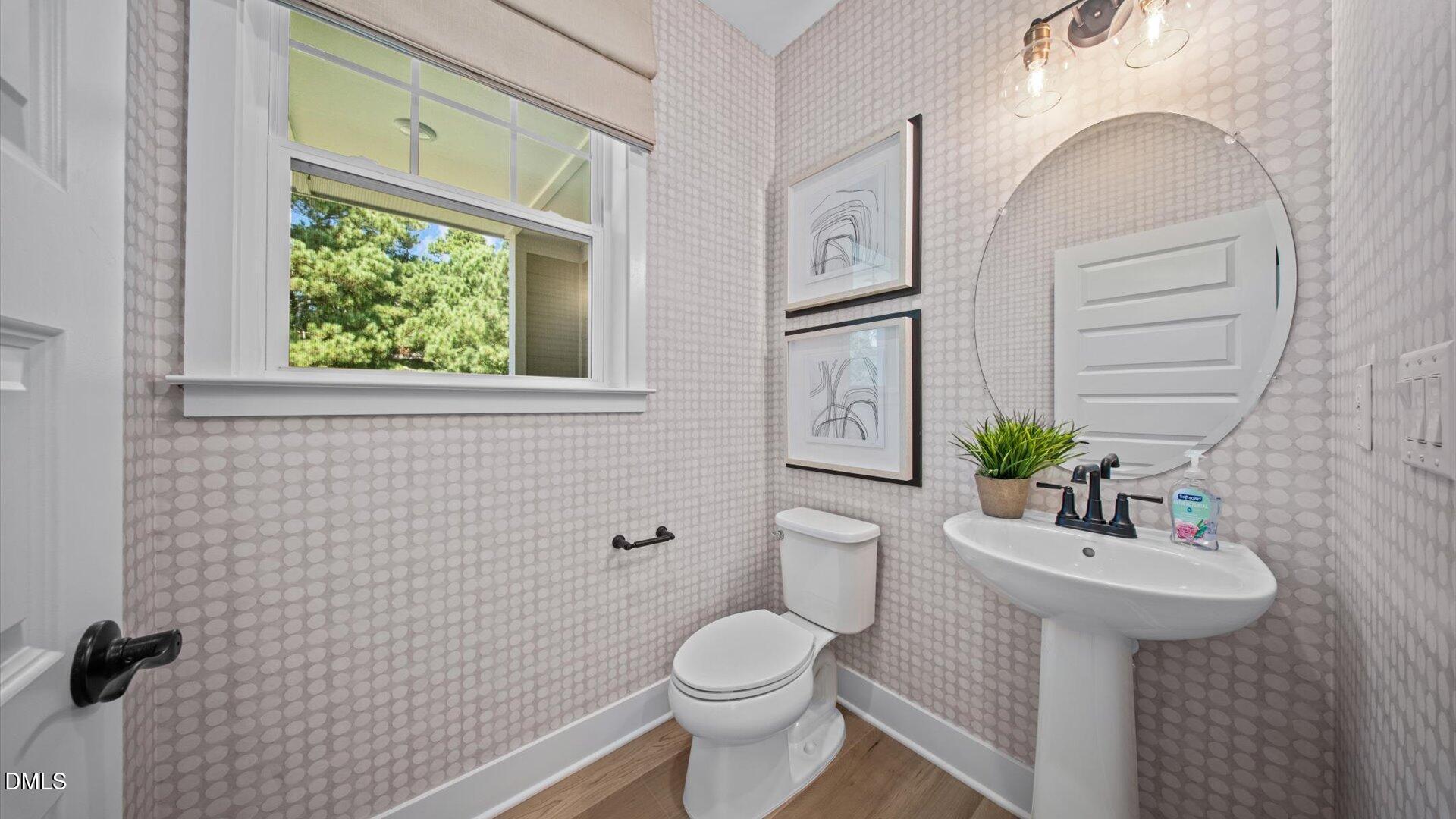 6046 Dunzo Drive Raleigh, NC 27617 - Photo 30 of 44 a bathroom with a sink a mirror a toilet and a window