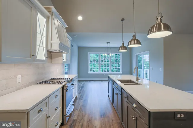 a kitchen that has a sink a stove and a wooden floor