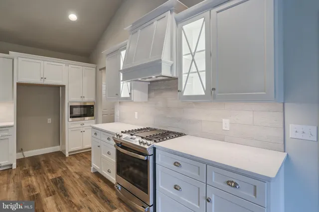 a kitchen with granite countertop a stove a sink dishwasher and a refrigerator with wooden floor