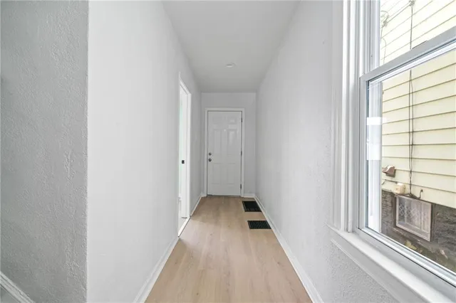 a view of a hallway with wooden floor and a window