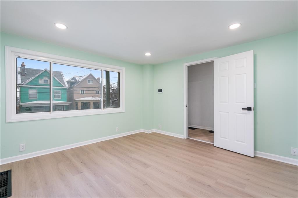 67 Ruth Street Pittsburgh, PA 15211 - Photo 4 of 26 an empty room with wooden floor and windows