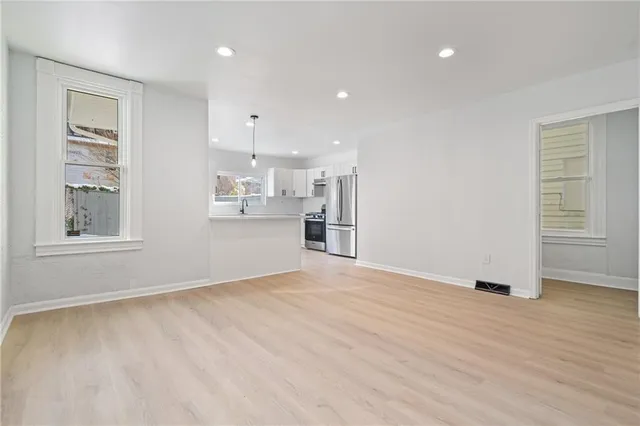 a view of an empty room with window and wooden floor