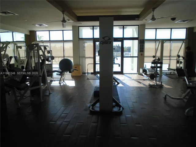 a view of a hallway to a livingroom with wooden floor and a bathroom