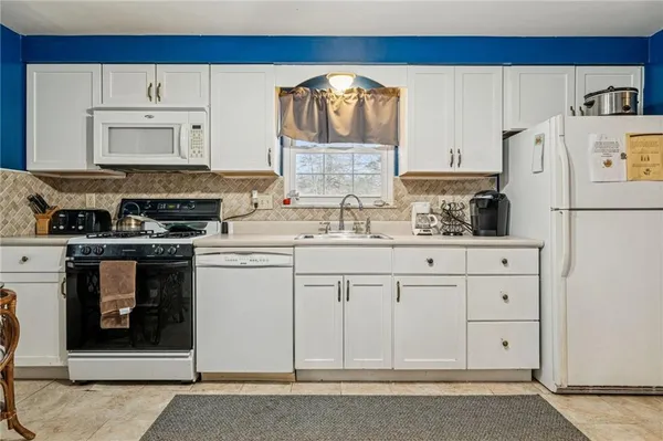 a kitchen with white cabinets and white appliances