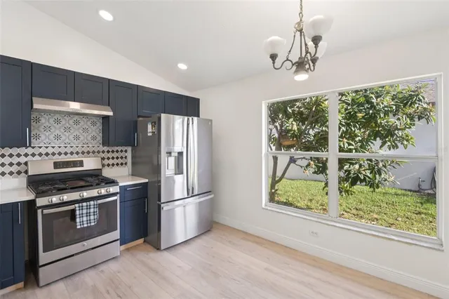 a kitchen with stainless steel appliances granite countertop a stove a refrigerator a sink and a wooden floors
