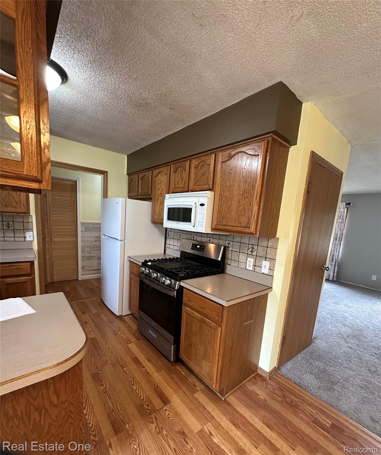2430 Coolidge Road Barryton, MI 49305 - Photo 21 of 29 Kitchen featuring wood-finish flooring, wood cabinetry, a tiled backsplash, and stainless steel range