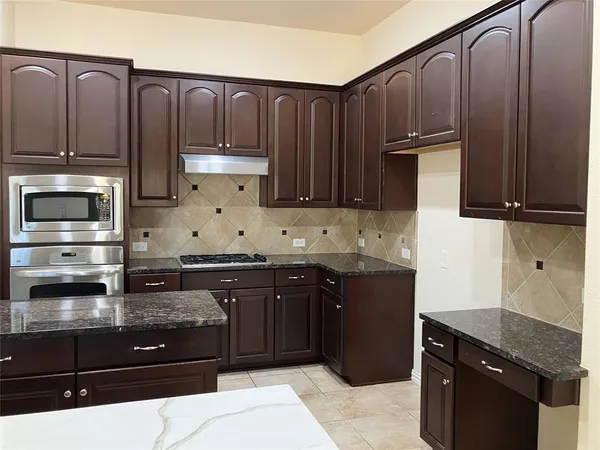 a kitchen with stainless steel appliances granite countertop wooden cabinets a refrigerator and a stove