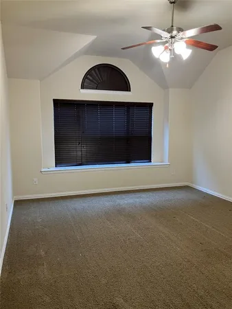 a view of an empty room with window and chandelier fan
