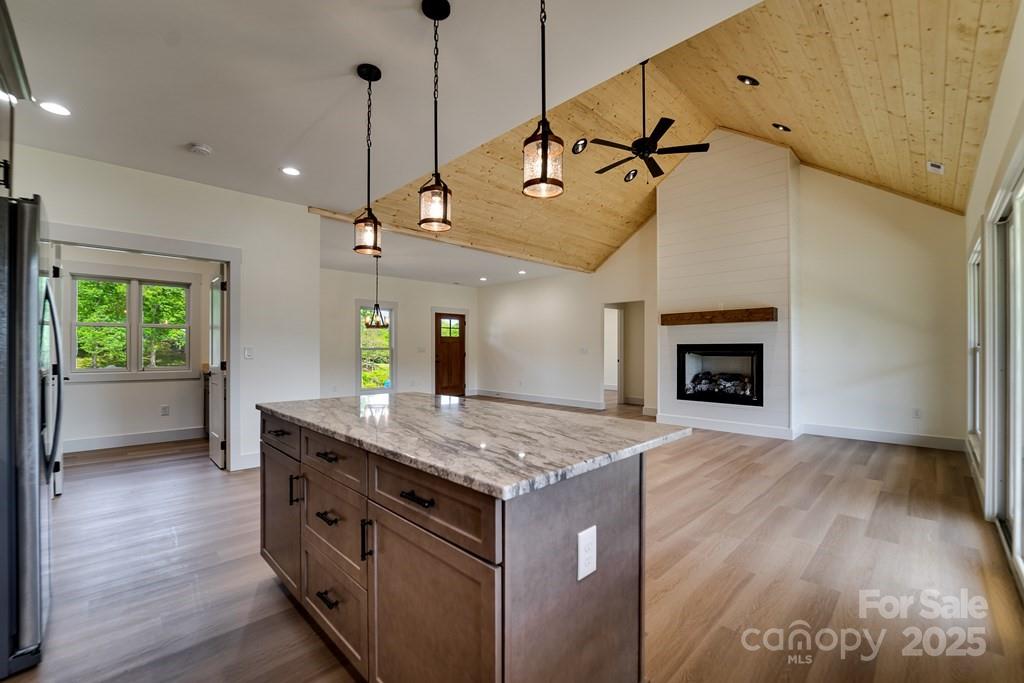 70 Knox Best Street Clyde, NC 28721 - Photo 11 of 33 a kitchen with kitchen island a wooden floor and a fireplace