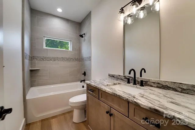 a bathroom with a granite countertop sink a toilet and bathtub