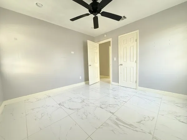 a view of an empty room with window and a kitchen