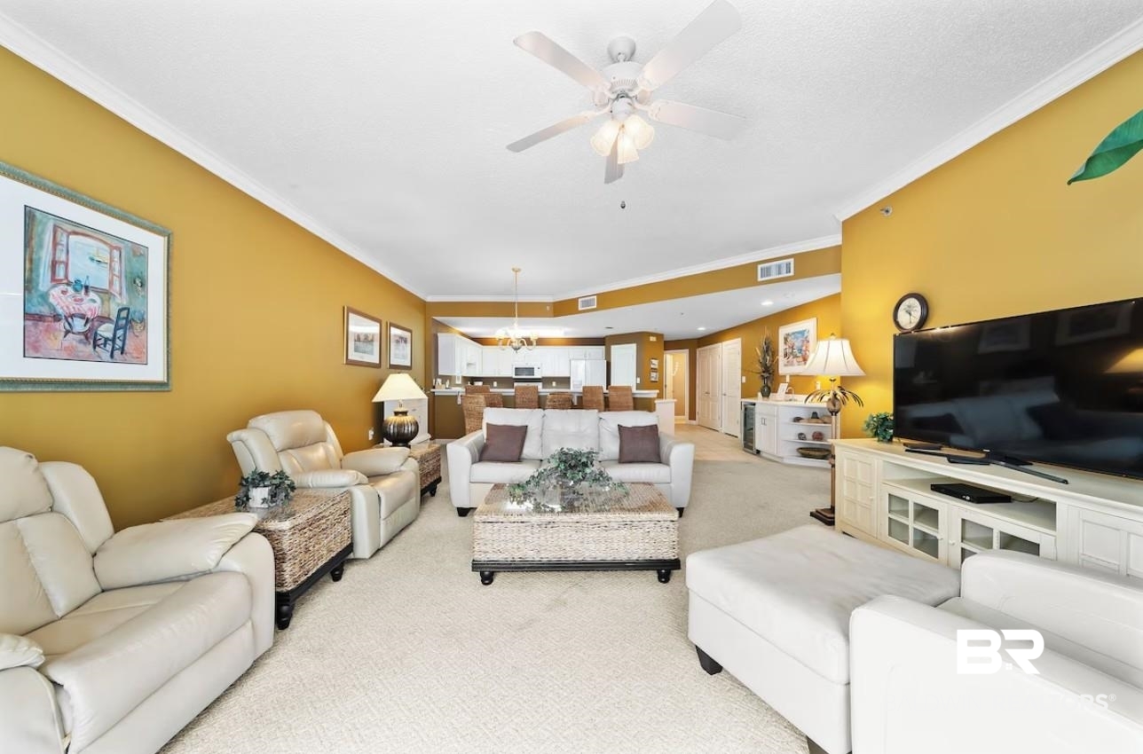 27770 Canal Road, Unit 2502 Orange Beach, AL 36561 - Photo 9 of 55 Carpeted living room featuring ornamental molding, a chandelier, and a ceiling fan