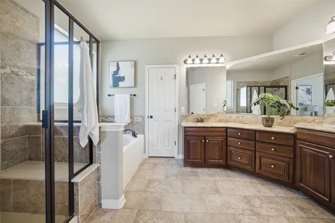 a spacious bathroom with a granite countertop sink mirror and a bathtub