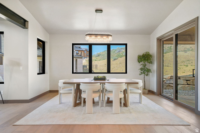 10646 North Reflection Ridge Hideout, UT 84036 - Photo 11 of 43 Dining area featuring light wood-finish flooring, a contemporary chandelier, multiple windows with black trim, and a sliding glass door