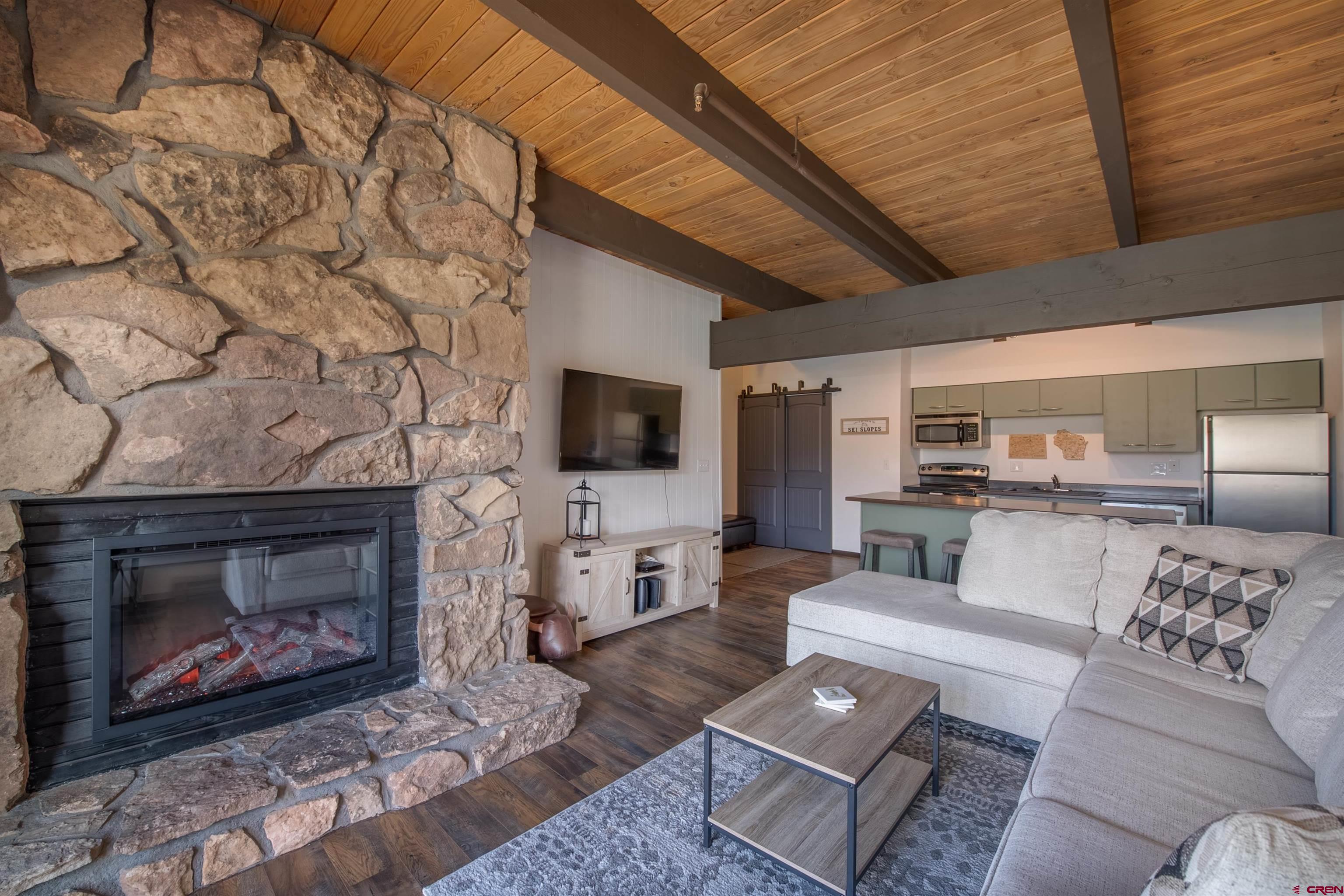 32 Hunter Hill Road, Unit B102 Crested Butte, CO 81225 - Photo 12 of 28 a living room with furniture a flat screen tv and a fireplace