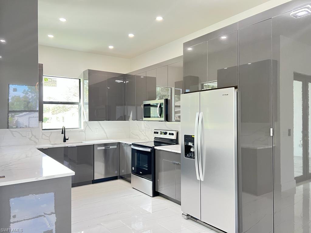 3302 East 3rd Street Lehigh Acres, FL 33936 - Photo 19 of 23 a large kitchen with cabinets and stainless steel appliances