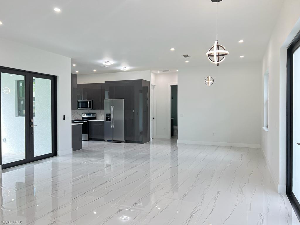 3302 East 3rd Street Lehigh Acres, FL 33936 - Photo 9 of 23 a view of a kitchen with a refrigerator and a kitchen counter top