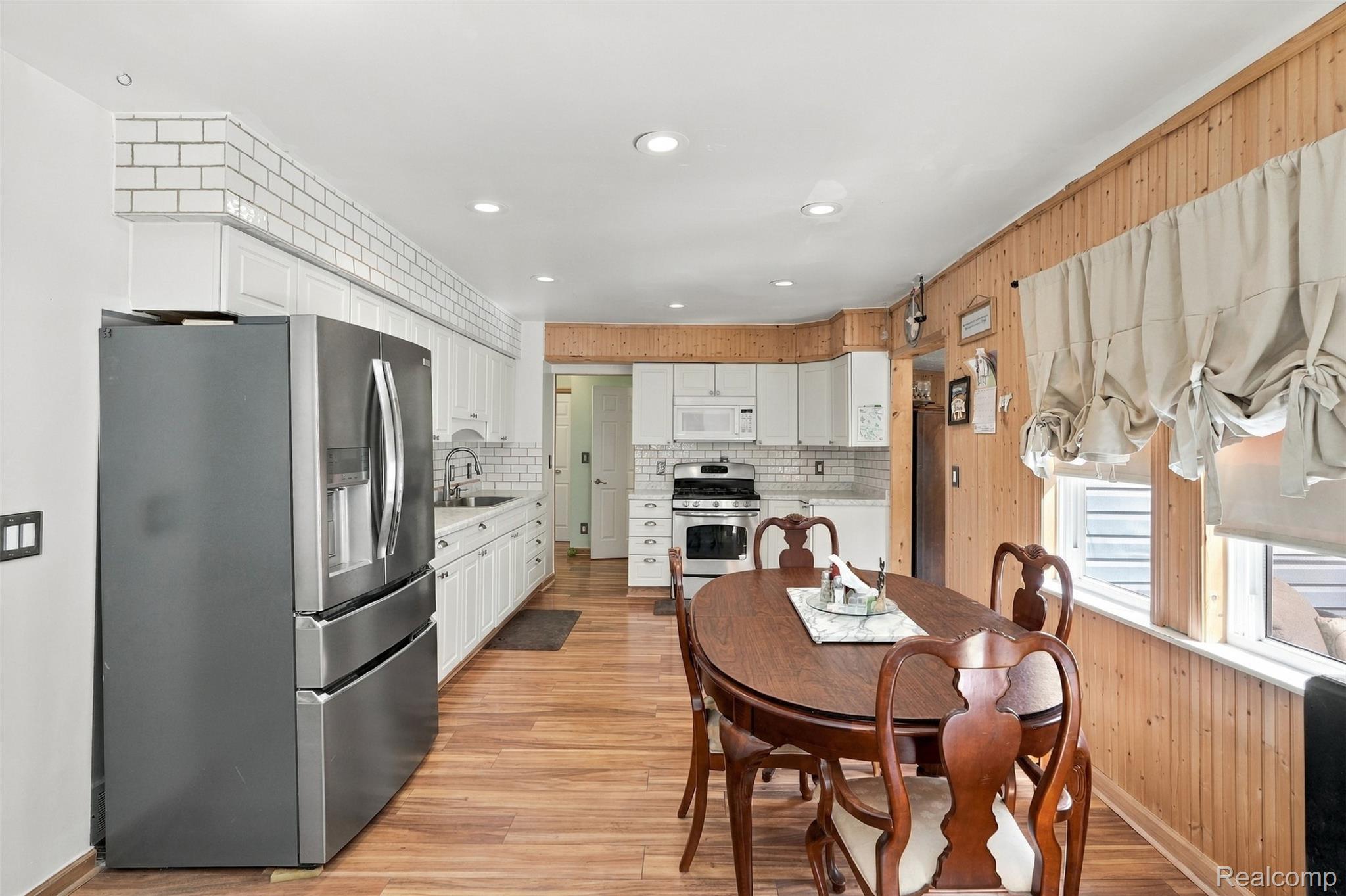 36739 Wick Road Romulus, MI 48174 - Photo 6 of 56 Kitchen with wood-finish flooring, white cabinetry, subway tile backsplash, and stainless steel appliances