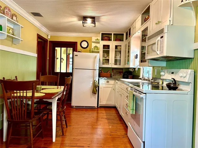 a kitchen with stainless steel appliances granite countertop a refrigerator a sink dishwasher a dining table and chairs with wooden floor