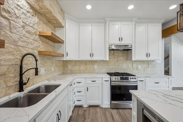 a kitchen with granite countertop a sink stainless steel appliances and cabinets