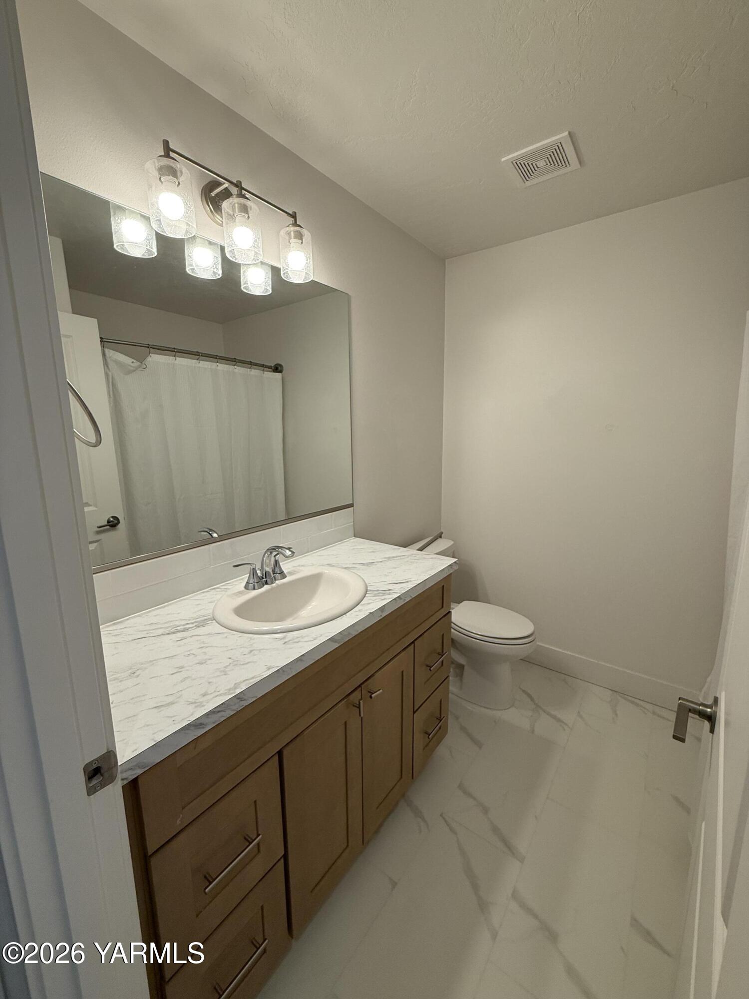 707 Grapevine Street Grandview, WA 98930 - Photo 11 of 14 a bathroom with a sink a large mirror and toilet