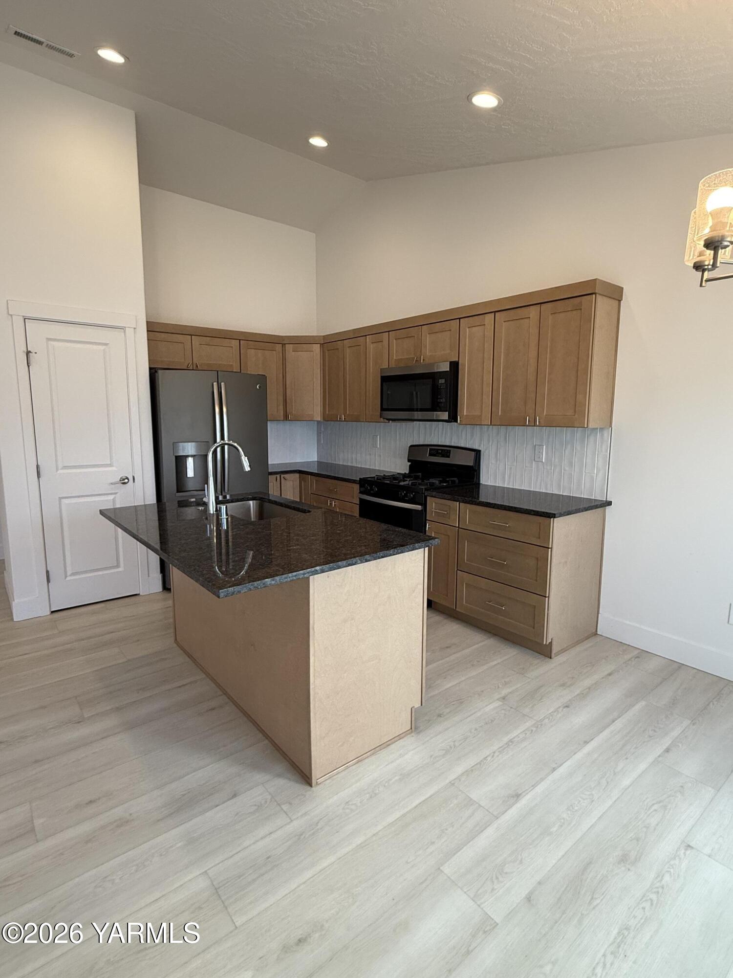 707 Grapevine Street Grandview, WA 98930 - Photo 4 of 14 a kitchen with stainless steel appliances a stove a microwave a sink and a refrigerator