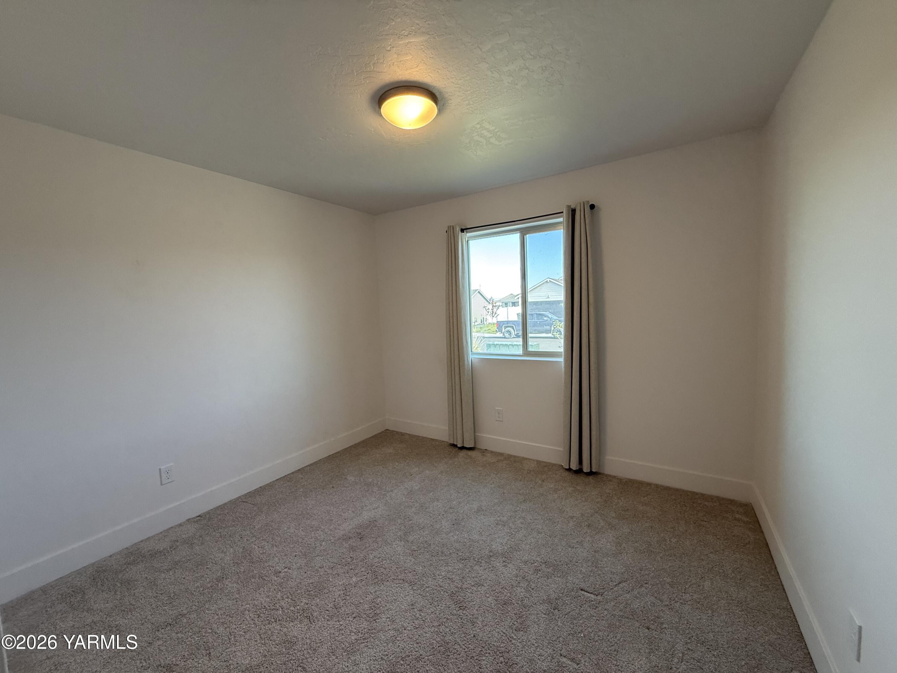 707 Grapevine Street Grandview, WA 98930 - Photo 10 of 14 an empty room with windows and closet