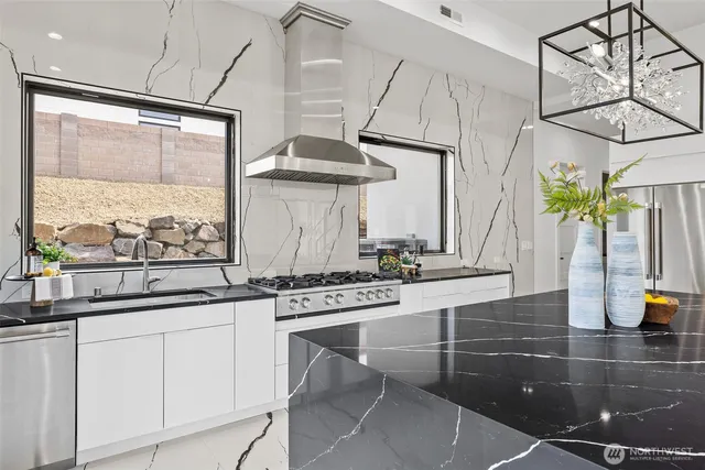 a kitchen with stainless steel appliances kitchen island granite countertop a stove a sink and white cabinets next to a window