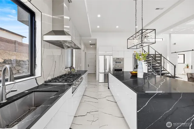 a large kitchen with kitchen island granite countertop a large window and stainless steel appliances