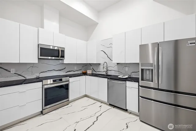 a kitchen with stainless steel appliances granite countertop a refrigerator stove a sink and dishwasher a oven with white cabinets