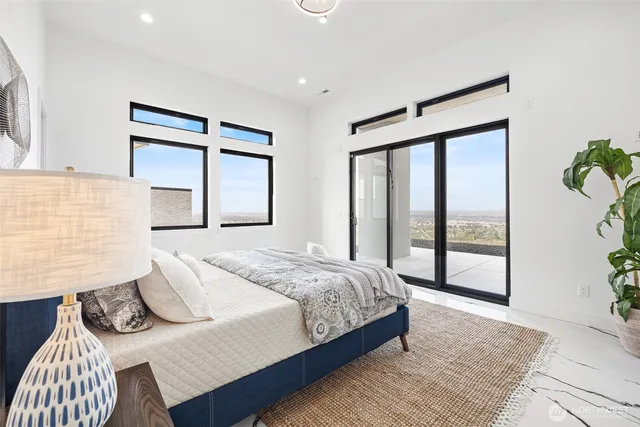a bedroom with a bed and a large window with potted plants
