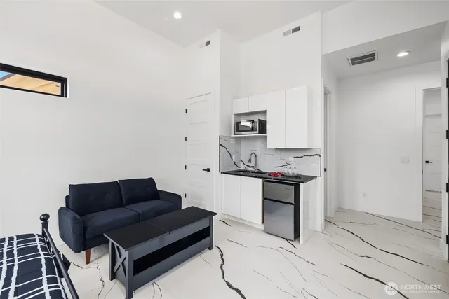 a living room with stainless steel appliances kitchen island granite countertop a sink and a stove