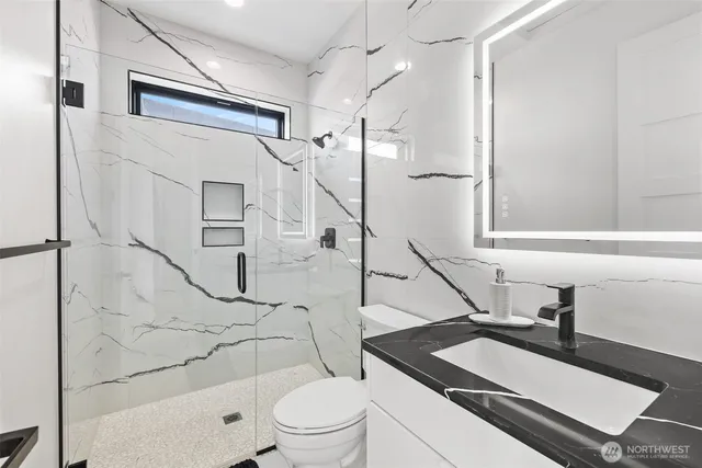 a bathroom with a granite countertop sink toilet a mirror and shower
