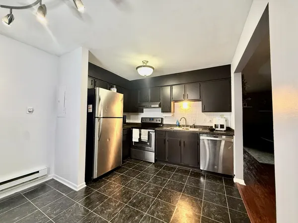 a kitchen with stainless steel appliances granite countertop a refrigerator a stove and a sink