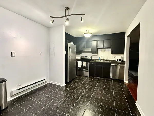 a kitchen with granite countertop a refrigerator a sink and white cabinets