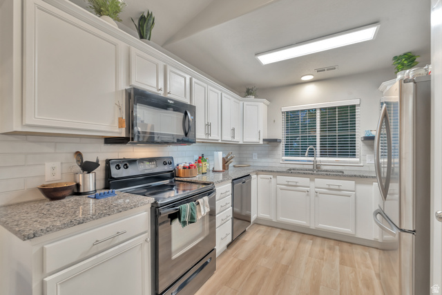 Undisclosed Address Ogden, UT 84403 - Photo 11 of 21 Kitchen with black appliances, white cabinetry, light stone counters, light wood finished floors, and backsplash
