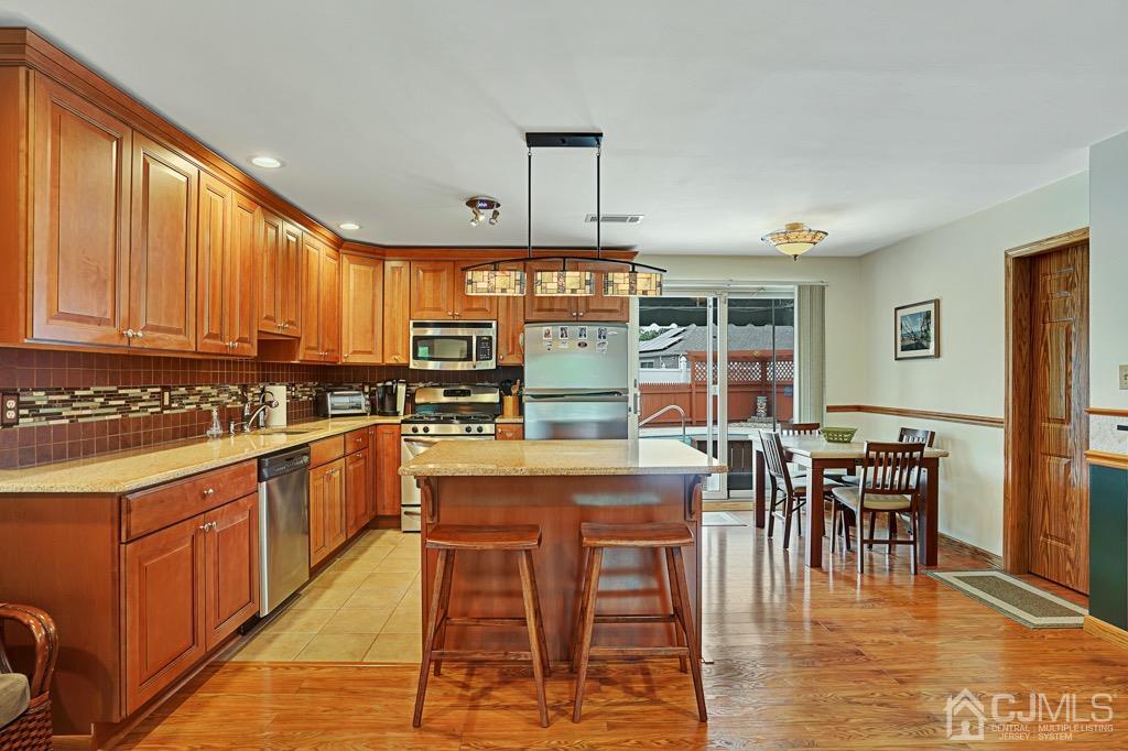 210 Oak Drive Middlesex, NJ 08846 - Photo 5 of 27 a kitchen with stainless steel appliances granite countertop a stove top oven a sink a dining table and chairs with wooden floor