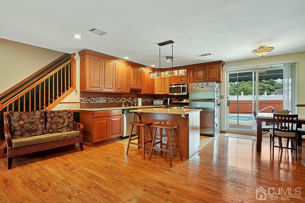 210 Oak Drive Middlesex, NJ 08846 - Photo 6 of 27 a kitchen with stainless steel appliances granite countertop a stove top oven a sink a dining table and chairs with wooden floor