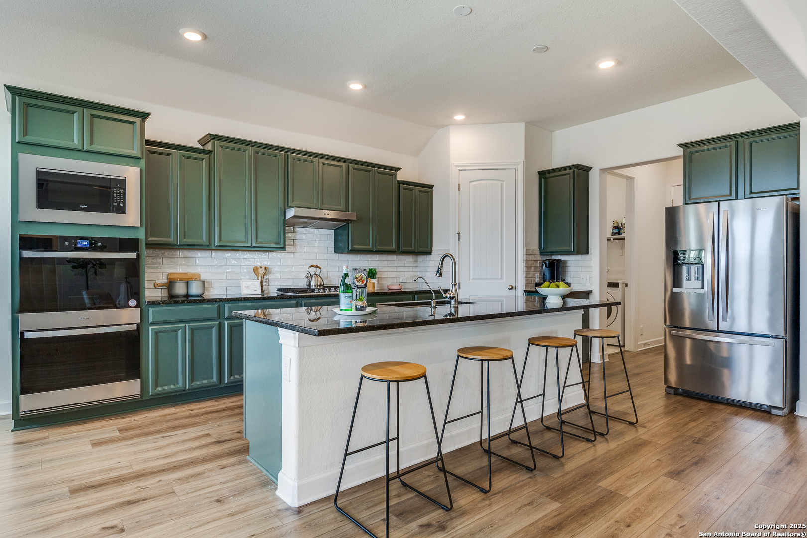 390 Rhapsody View Spring Branch, TX 78070 - Photo 10 of 39 a kitchen with stainless steel appliances granite countertop a refrigerator a stove top oven and a sink with wooden floor