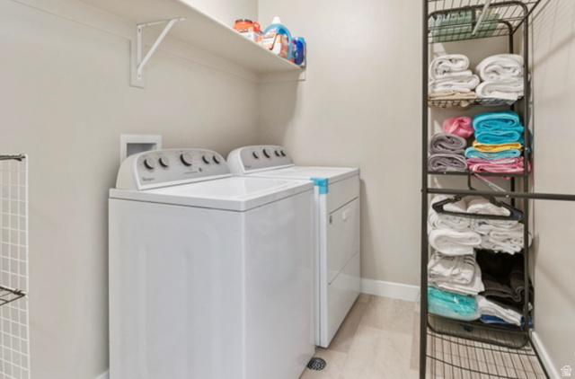 1295 East Granite Peak Road Eagle Mountain, UT 84005 - Photo 34 of 35 Dedicated laundry space featuring a white top-load washer and dryer set, a wall-mounted storage shelf, and light wood-finish flooring