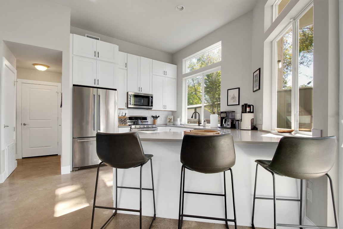 1905 Alegria Road, Unit B Austin, TX 78757 - Photo 11 of 25 Designed for both style and function, this bright kitchen features KitchenAid appliances, quartz countertops, and custom shaker cabinets. Large windows fill the space with natural light and offer a peaceful view of the private backyard.