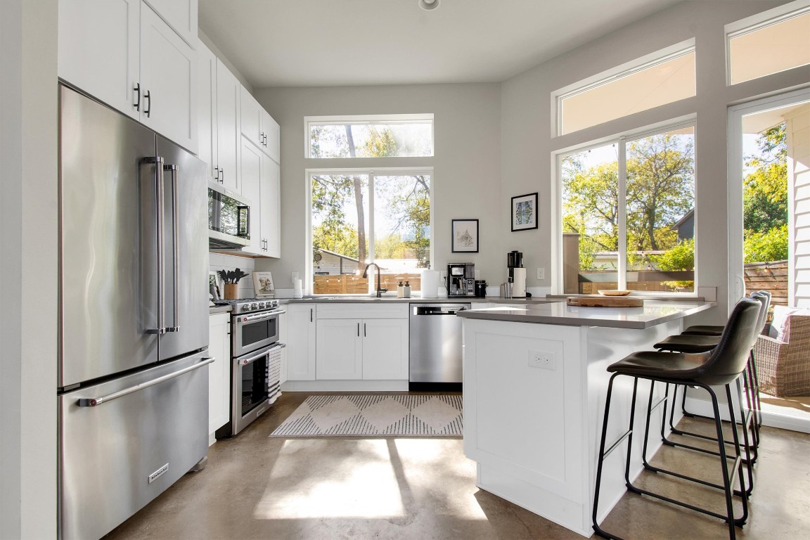 1905 Alegria Road, Unit B Austin, TX 78757 - Photo 12 of 25 Designed for both style and function, this bright kitchen features KitchenAid appliances, quartz countertops, and custom shaker cabinets. Large windows fill the space with natural light and offer a peaceful view of the private backyard.