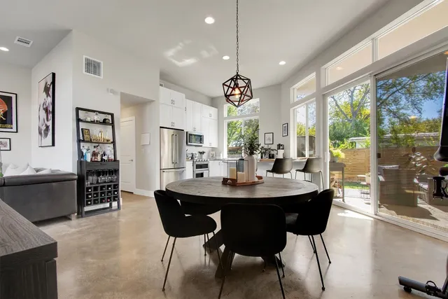 a kitchen with stainless steel appliances granite countertop a refrigerator a stove a dining table and chairs with wooden floor