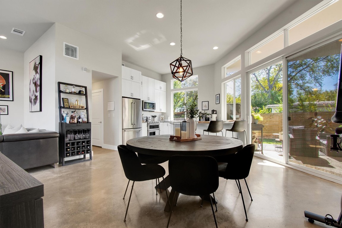 1905 Alegria Road, Unit B Austin, TX 78757 - Photo 10 of 25 A bright, open-concept living and dining area with 14’ ceilings, polished concrete floors, and walls of windows that bring the outdoors in. Perfect for entertaining, relaxing, or enjoying the seamless flow from the kitchen to the private patio.