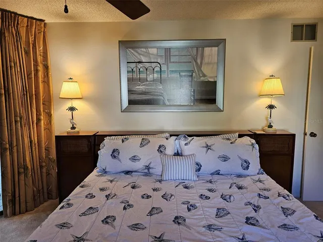 a bedroom with a large bed and a lamp on dresser