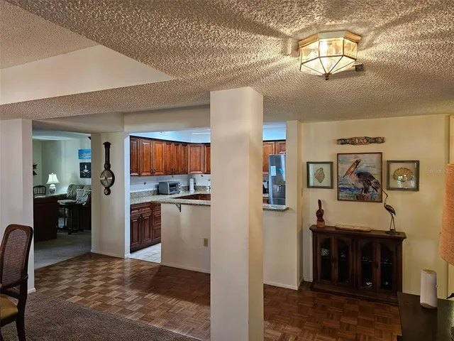 a living room with stainless steel appliances furniture a chandelier and a view of kitchen