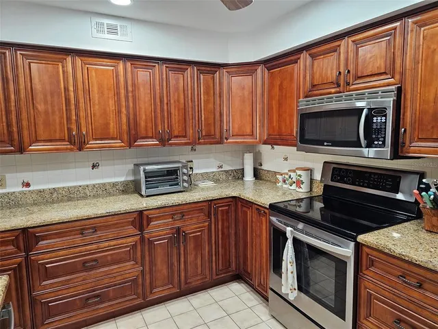 a kitchen with granite countertop a stove top oven microwave and cabinets